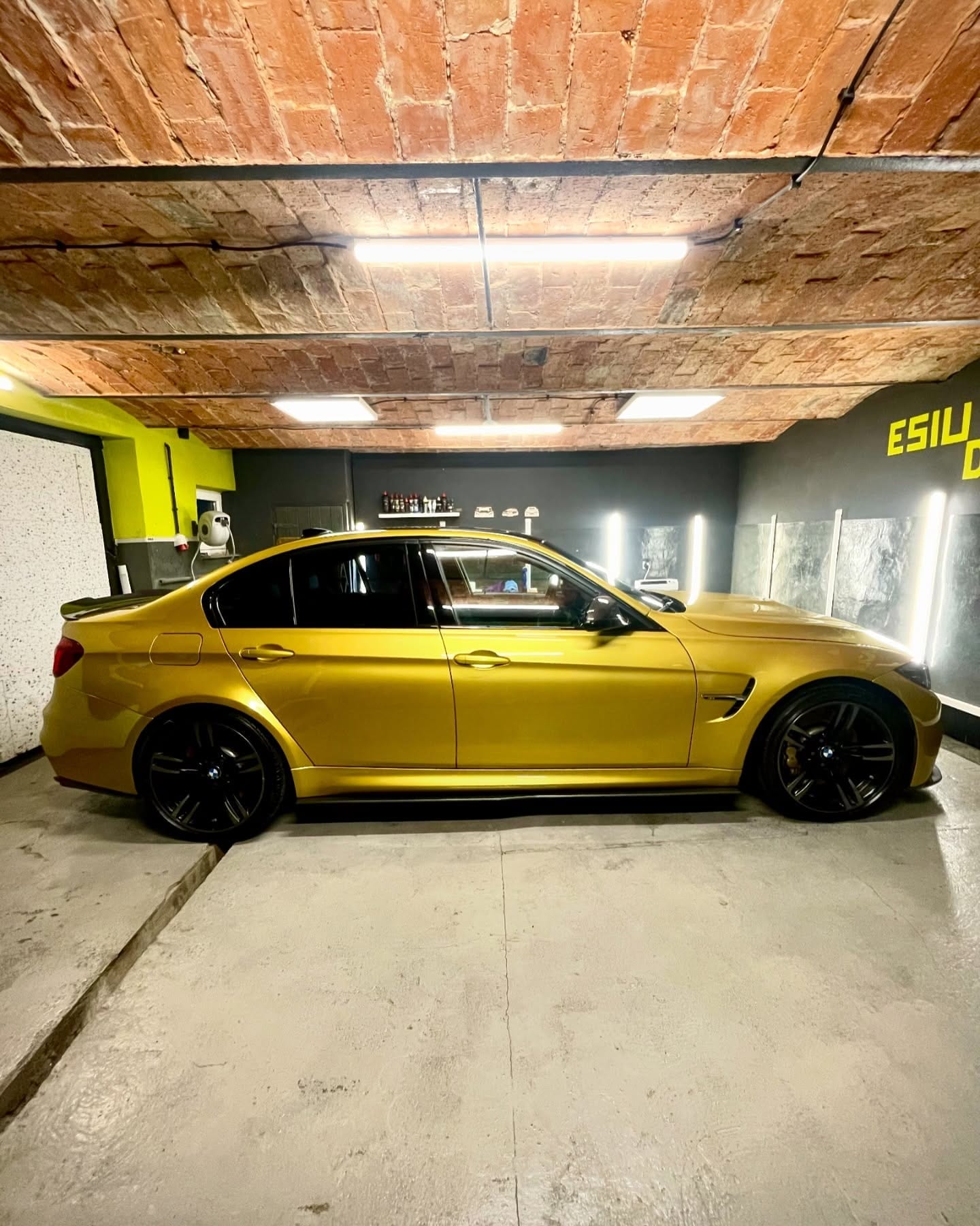BMW M3 F80 Austin Yellow z boku, ustawione pod ceglanym sklepieniem studia